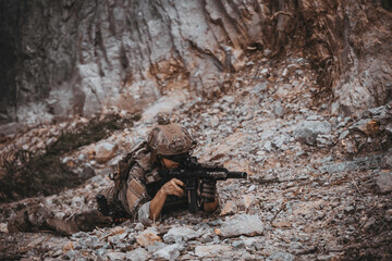 Obraz premium Armed tactical operator aiming rifle during military combat mission in outdoor nature environment. Professional private military contractor conducting security patrol operation in forest wilderness.