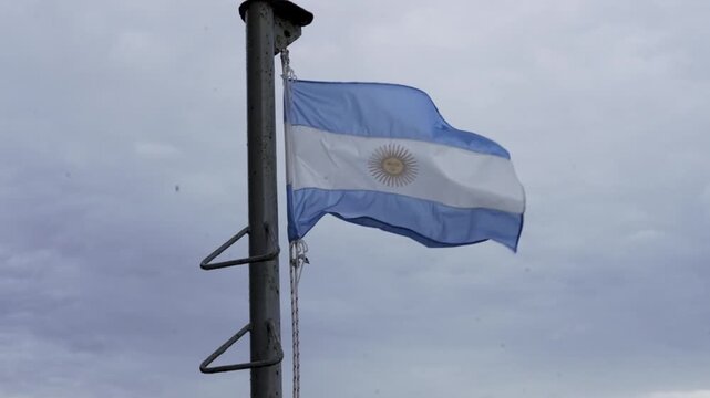 Bandera argentina flameando en c&aacute;mara lenta sobre un m&aacute;stil, plano detalle de s&iacute;mbolo patrio, identidad nacional, patriotismo, celebraci&oacute;n, historia y cultura de Argentina