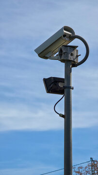 Security camera monitoring urban area against blue sky