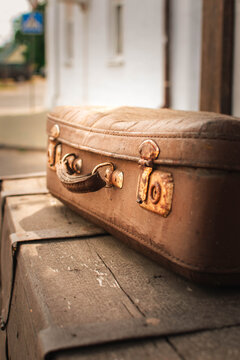vintage brown suitcase with leather handle on old wooden chest