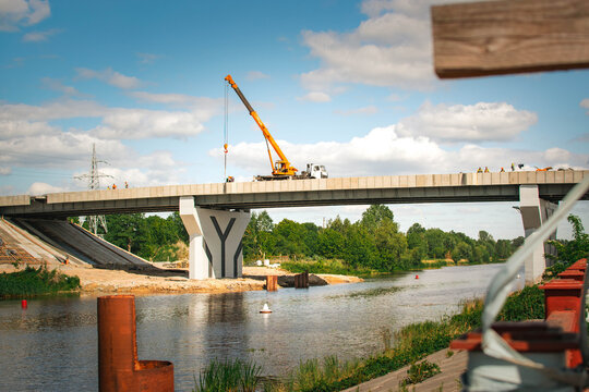 bridge construction over river with crane and workers on sunny day