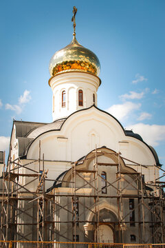 orthodox church restoration with golden dome and scaffolding under blue sky