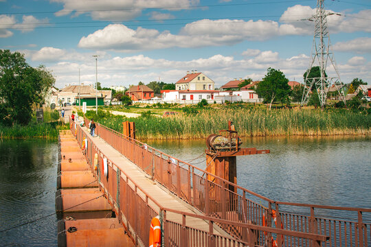 floating pontoon bridge across river with reeds and town landscape