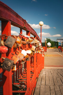 wooden pedestrian bridge with colorful love locks on sunny day