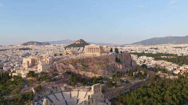 Amazing aerial shot slowly revealing the ancient acropolis of athens, with the parthenon temple and the odeon of herodes atticus, showing the entire cityscape during a sunny day in greece