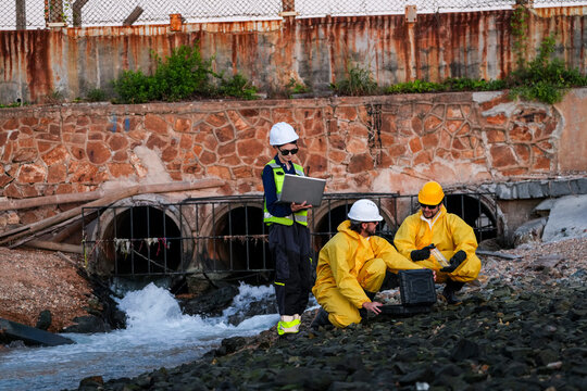 Engineering team in protective gear conducting an environmental audit, water quality sampling, and site survey at an industrial drainage outfall to ensure regulatory compliance.