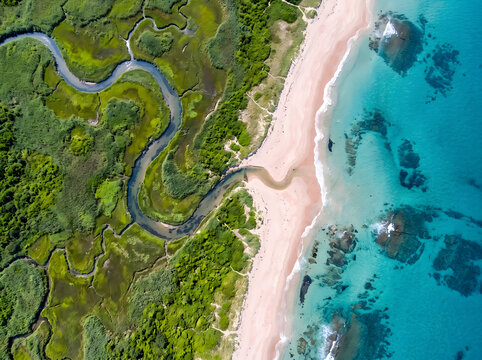 Aerial view of a serene beach with a winding river flowing into the ocean