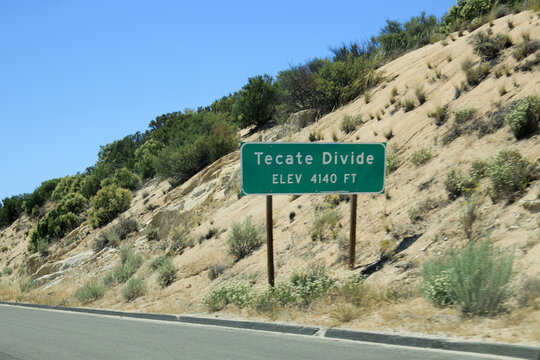 Tecate Divide sign marking 4140-foot elevation along westbound Interstate-8 with clear blue California sky and rugged terrain; copy space