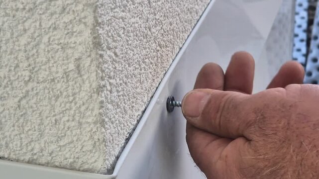 Close up video of inserting a screw into a metal roof flashing after drilling at normal speed