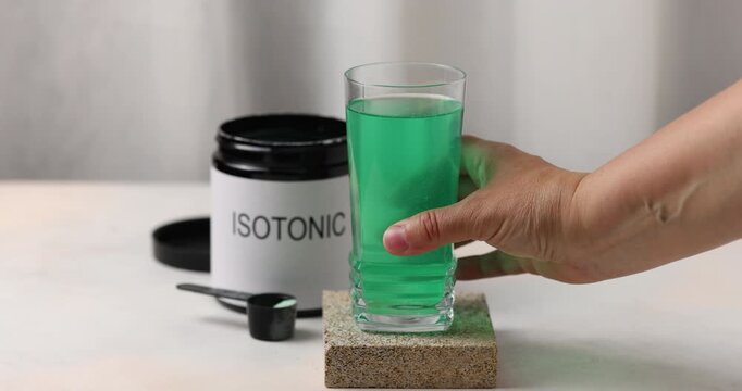 Isotonic sport drink. Aminoacid powder in glass on stone background with measuring cup	
