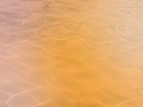 Warm atmospheric pool water background showing realistic sun caustics over an orange and terracotta field