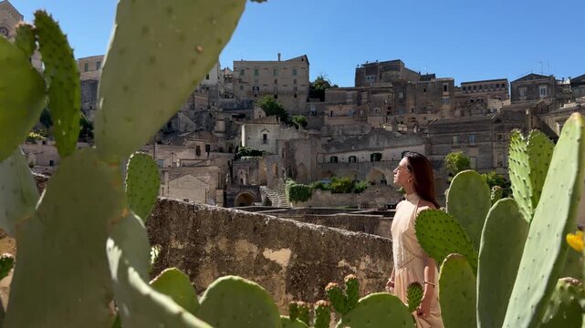 Elegant Woman Admiring Sassi di Matera Panorama Through Prickly Pear Cactus Italy Slow Motion UNESCO Historic City
