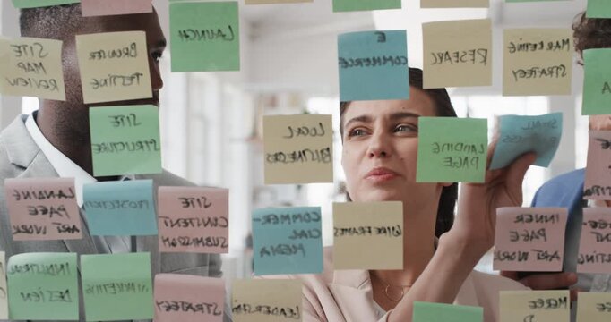 Businessman, sticky note and team at office with glass wall, review or planning at marketing company. People, talk or group with board, feedback or project management launch at advertising agency