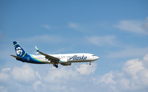 Alaska Airlines aircraft Boeing 737 airborne over the Dallas Fort Worth International Airport (DFW). Blue skies and white clouds.