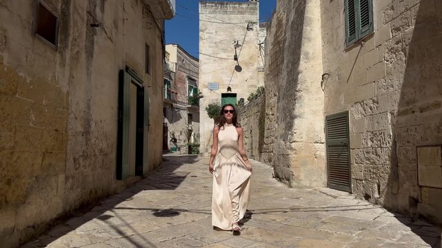Confident Woman Walking Toward Camera in Sunny Matera Ancient Street UNESCO Italy
