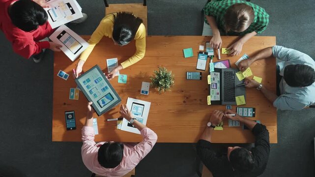 Team working at Ux Ui design for mobile phone interface while manager hand out document about wireframe prototype. Top view of project manager explain or brainstorm idea about software. Convocation.