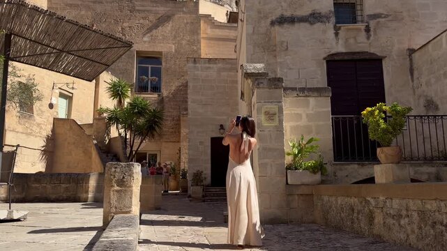 Woman Tourist Taking Photo in Ancient Matera Courtyard with Palm Tree UNESCO Italy