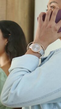 Vertical video: Entering woman holding purple phone to ear at home friend in green puff top smiling