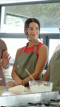 Vertical video: Listening woman in apron nodding in kitchen with bowl as left speaker instructing