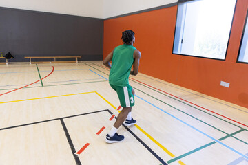 Naklejka premium Basketball player wearing green uniform number 3 standing on wood gym court with sport lines