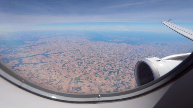 Looking out from passenger aircraft window, patches of cultivated land of Loiret and Essonne departments seen down. Airliner fly at cruise altitude, approaching Paris city from south