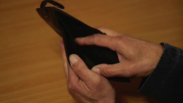 Man checks empty wallet after expenses and financial losses.