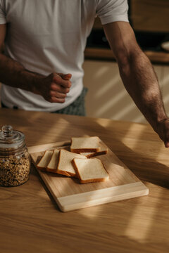 Man preparing breakfast toast and granola in morning light