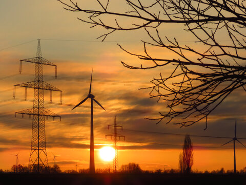 Windkraftanlagen und Strommasten im Sonnenuntergang,  sie symbolisieren oft die Energiewende und den Ausbau erneuerbarer Energien. Hier in der Soester B&ouml;rde, Deutschland, Nordrhein-Westfalen.