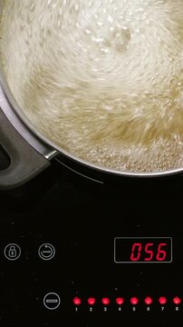 Boiling pasta in pan on induction oven. Closeup. Top View. Vertical footage
