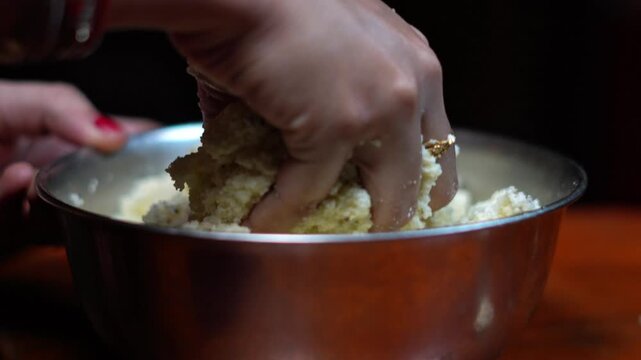 Kneading Fresh Cottage Cheese Dough in Metal Bowl Close Up. Hand Mashing Chhena Curds for Traditional Indian Sweet Preparation. Cottage Cheese Grains for Baking Close Up.