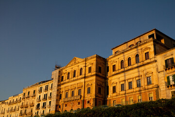 Fototapeta premium Historic center of Siracusa, Sicily, glowing at sunset along the scenic seafront during a summer vacation.