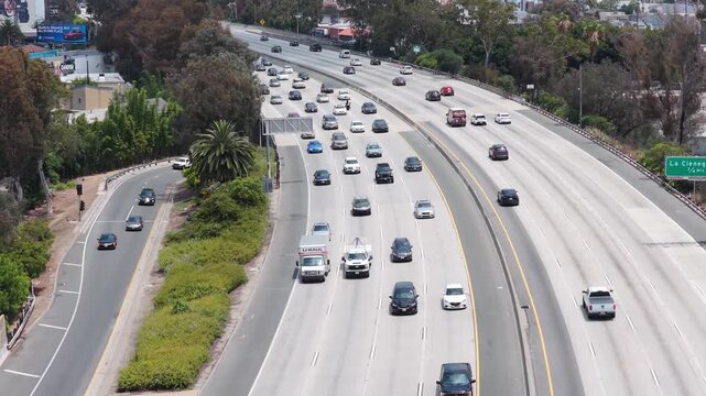 Los Angeles freeway traffic showing vehicles moving through busy interchange with downtown skyline background, transportation and urban commute in California