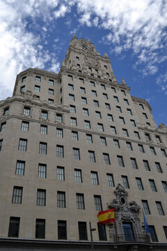MADRID, SPAIN - JUNE, 4, 2026. Grand facade of the telefonica building in madrid with clock tower and national flags over entrance against dramatic sky