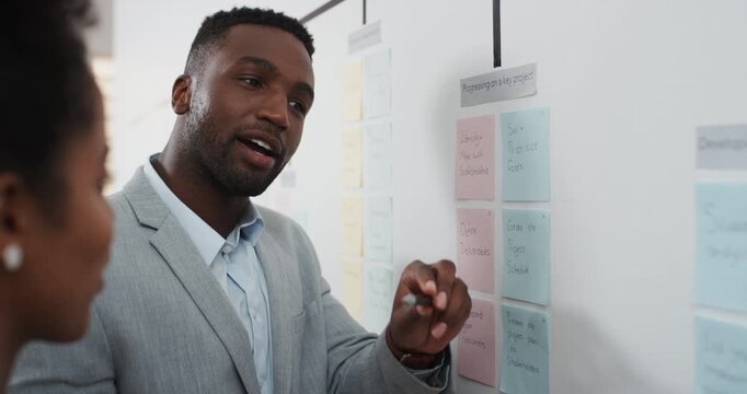 Man, talking and notes on whiteboard in meeting for training, planning and agenda for audit. Office, team and discussion with storyboard for coaching, brainstorming and ideas for investment proposal