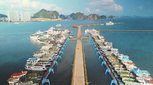 Ha long bay harbor with numerous cruise ships and tourist boats docked at long piers, ready for excursions among the famous limestone karsts and islands of vietnam