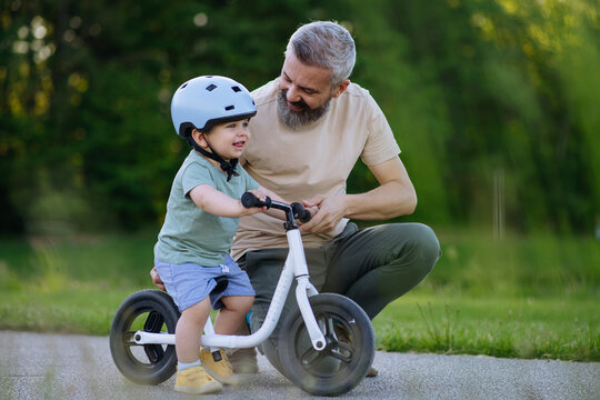 Dad encouraging young child to build confidence on balance bike.
