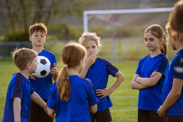 Naklejka premium Young football players discussing strategy before match on sports field.
