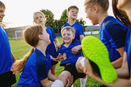 Young football teammates celebrating goal during youth soccer match.
