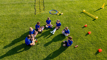 Young soccer players taking break during football practice on sports field. © Halfpoint