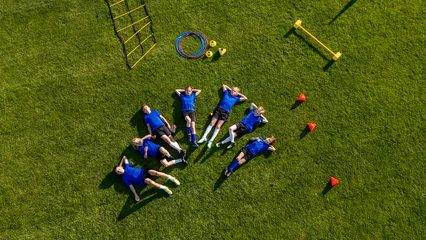Fototapeten Pony Young soccer players taking break during football practice on sports field.  © Halfpoint