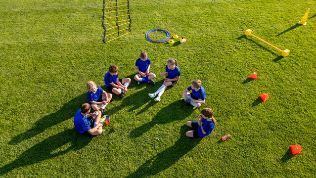 Young soccer players taking break during football practice on sports field.