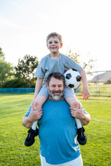 Obraz premium Dad and son sharing passion for football and active lifestyle.