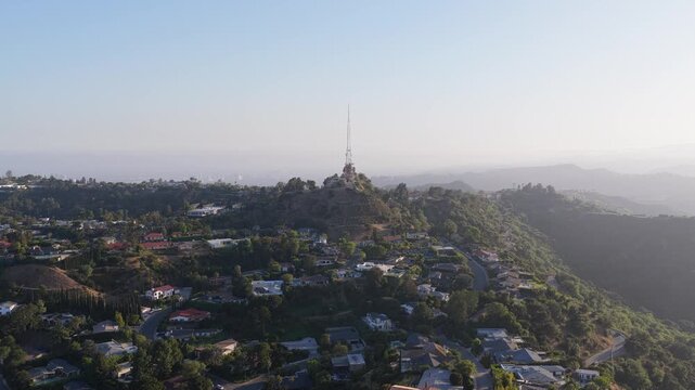 Scenic flight over Hollywoodland featuring Mount Lee and Hollywood Hills neighborhood, revealing urban landscape of Los Angeles with golden hour sun and morning mist