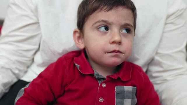 Cute toddler boy eating banana and using smartphone