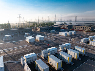 Fototapeta premium Power substation with energy storage containers and transmission towers under clear sky