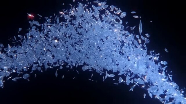 Slow motion tracking shot of glass shards exploding and swirling across dark studio black backdrop into cascading crystal particle stream