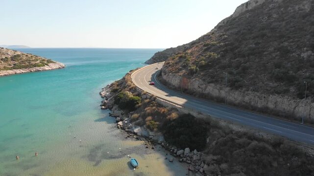 Aerial view of beach and road in Paralia Lomvarda beach near Athens, Greece and seaside. Drone view from above. Sea and coast with sandy beach. Summer destination on the Mediterranean Sea, Europe
