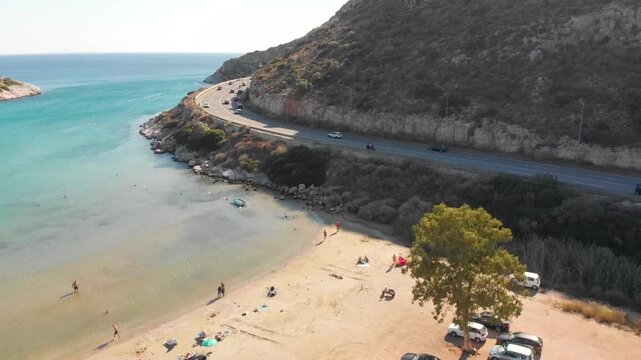 Aerial view of beach and road in Paralia Lomvarda beach near Athens, Greece and seaside. Drone view from above. Sea and coast with sandy beach. Summer destination on the Mediterranean Sea, Europe
