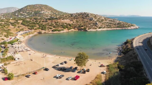 Aerial view of beach and road in Paralia Lomvarda beach near Athens, Greece and seaside. Drone view from above. Sea and coast with sandy beach. Summer destination on the Mediterranean Sea, Europe
