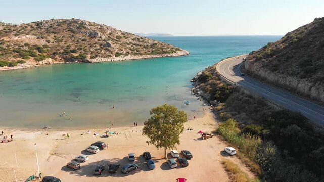 Aerial view of beach and road in Paralia Lomvarda beach near Athens, Greece and seaside. Drone view from above. Sea and coast with sandy beach. Summer destination on the Mediterranean Sea, Europe
